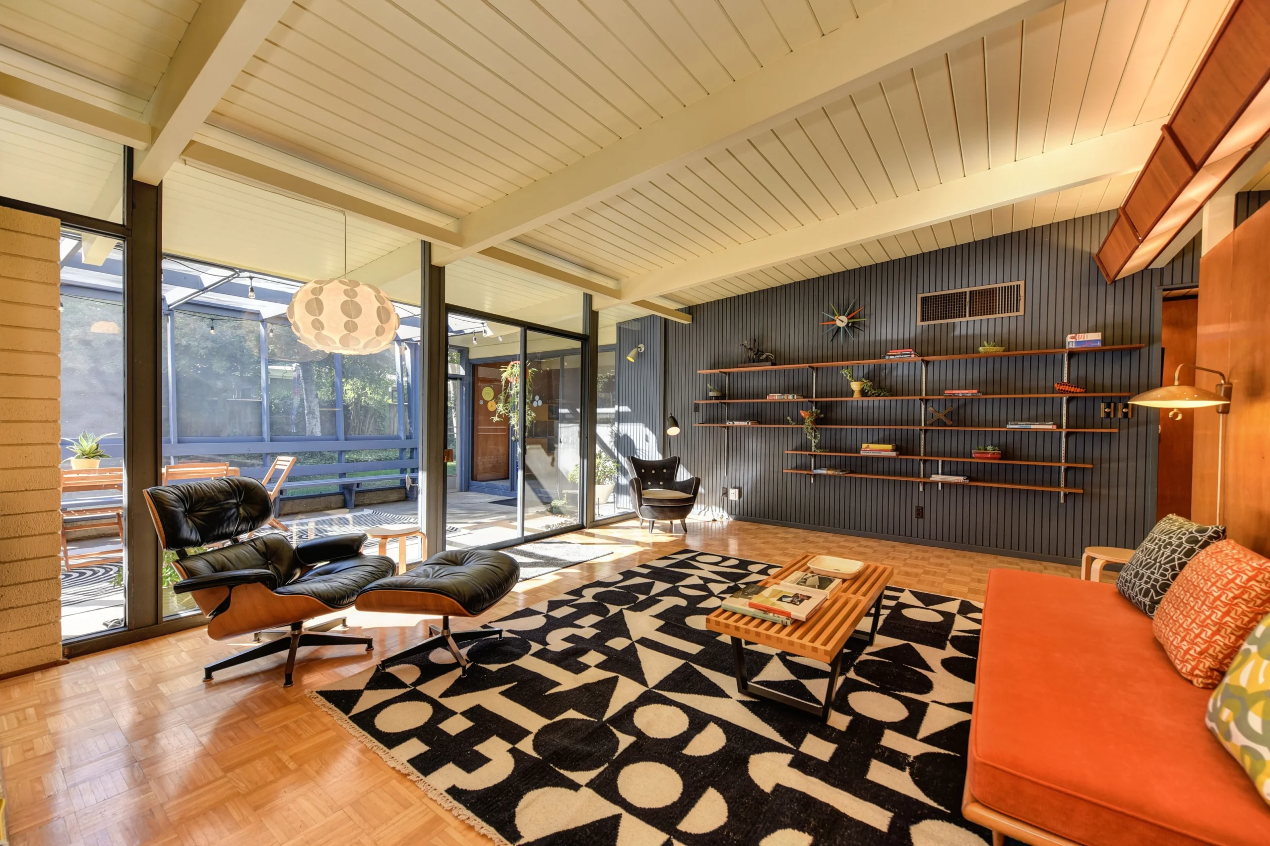 Mid-century modern living room with orange sofa, lounge chair and geometric rug
